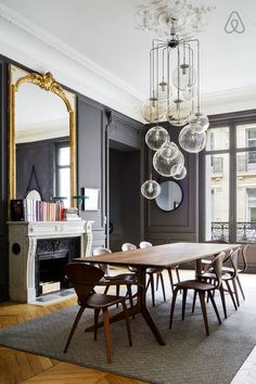 an elegant dining room with dark walls and wood flooring, chandelier above the table