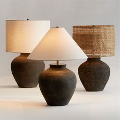 three vases with lamps on them sitting next to each other