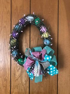 a wreath is hanging on the wall next to a wooden door with polka dot ribbon