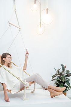 a woman sitting on a swing chair with her legs crossed and feet up in the air