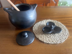 a wooden table topped with a black vase and two small bowls on top of it