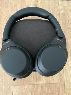 two black headphones sitting next to each other on a white counter top in front of a wall