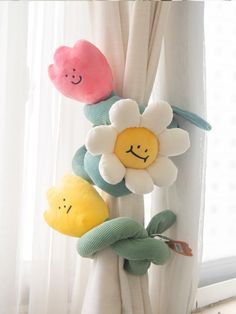 three stuffed toys are hanging on the curtain