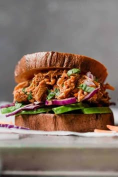 a pulled pork sandwich with lettuce and red onions