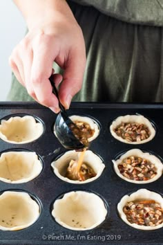 a person pouring sauce on top of mini pies in a muffin tin lined with paper