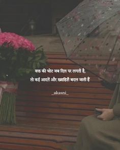 a woman sitting on a bench with an umbrella over her head and flowers in front of her