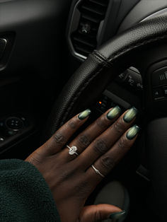 a woman's hands on the steering wheel of a car with green fingernails and nail polish