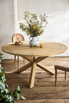 a wooden table with two chairs and a vase filled with flowers sitting on top of it