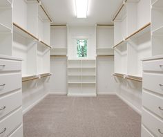 an empty walk - in closet with white shelves and beige carpeted flooring is shown