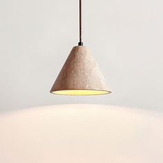 a light hanging from a ceiling with a white wall behind it and a brown cord on the end