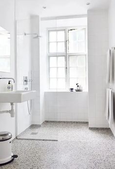 a bathroom with white walls and floor tiles