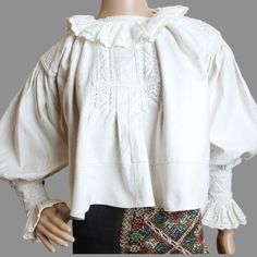 This is an antique Romanian blouse, originating from Transylvania, Bihor and crafted by hand, most likely between the 1930s and 1960s. The blouse is constructed from a thick, hand-woven fabric, resembling denim, and is adorned with stunning white cotton hand embroidery on the shoulders, cuffs, chest and ruffles . This particular blouse is versatile and can fit sizes XXS-XS, as well as German sizes 34-36.  The neck measures 33 cm (13 inches), while the distance from neck to shoulder seam is 14 cm (5.5 inches), and the circumference around the shoulder seam is 36 cm (14.17 inches). Additionally, the sleeve length from the neck measures 58 cm (22.8 inches), complete with a frill of 7 cm (2.75 inches). From armpit to armpit, the blouse measures 62 cm (24.4 inches), and has a length of 49 cm (1 Traditional Fitted Blouse For Daywear, Fitted Traditional Blouse For Daywear, Folk Style Fitted Cotton Peasant Top, Folk Style Peasant Top With Boho Collar, Fitted Cotton Folk Peasant Top, Traditional Long Sleeve Cotton Peasant Top, Peasant Style Cotton Blouse With Yoke, Peasant Style Cotton Blouse With Yoke Detail, Peasant Cotton Blouse With Ruffles