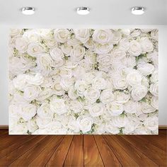 white roses on a wall in an empty room with wooden floor and lights above it