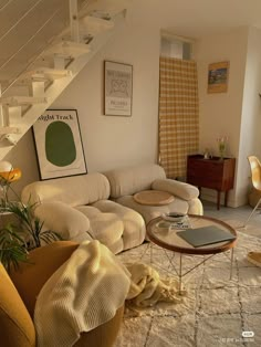 a living room filled with furniture next to a stair case and table on top of a rug