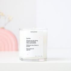 a white candle sitting on top of a table next to a vase with flowers in it