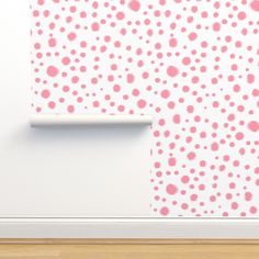 a white wall with pink and red polka dots on it, next to a wooden floor