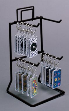 a set of four keychains hanging from a metal rack with cards on it