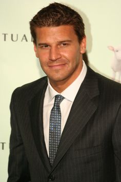 a man in a suit and tie smiling at the camera