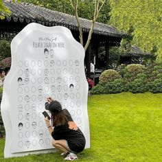 a woman kneeling down next to a giant white sign