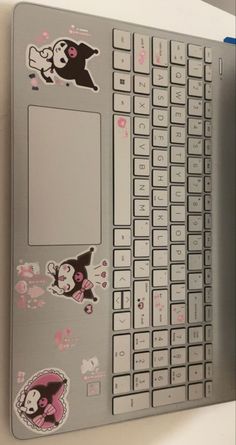 a laptop computer with stickers on the keyboard and back cover is sitting on a desk