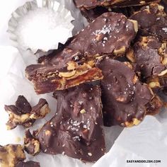 pieces of chocolate with nuts and sea salt on top in paper wrapper, ready to be eaten