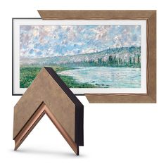 a painting hanging on the wall next to a frame with an image of a lake