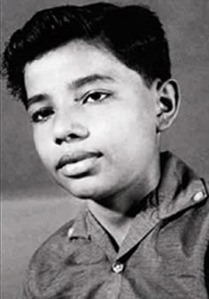 a black and white photo of a young boy with short hair wearing a polo shirt