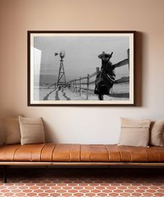 a black and white photo hangs on the wall next to a leather bench with pillows