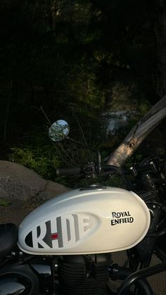 a white and black motorcycle parked next to a forest