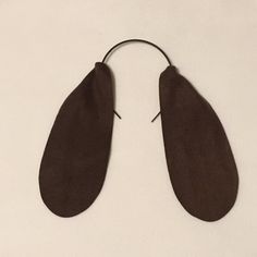 two pairs of brown leather ear hooks on a white surface with one pair hanging from the end