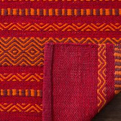 two red and orange rugs sitting next to each other on a wooden table top