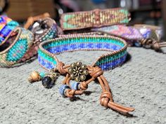 Bead Loom Leather Wrap Bracelet Blue Green Feather Blanket Boho Bracelet Bohemian Jewelry Aerieanna's Wristcraft This is a bead loom leather wrap bracelet made with naturally dyed (veggie) golden brown leather from the USA.  The beads are shades of green and blue. The button is brass plated pewter in a beaded flower design. Glass and stone dangles with feather charm. This bracelet closes at about 7 1/4" and 8 1/4". Adjustable Multicolor Artisan Wrap Bracelet, Bohemian Adjustable Wrap Bracelet With Round Beads, Festival Artisan Wrap Bracelet With Colorful Beads, Adjustable Bohemian Wrap Bracelet With Round Beads, Artisan Multicolor Wrap Bracelet For Festival, Artisan Wrap Bracelet With Round Beads For Festivals, Adjustable Bohemian Wrap Bracelet, Beaded Wrap Bracelet For Festivals, Bohemian Blue Wrap Bracelet With Colorful Beads