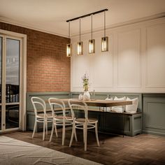 a dining room table with four chairs and a bench in front of a brick wall