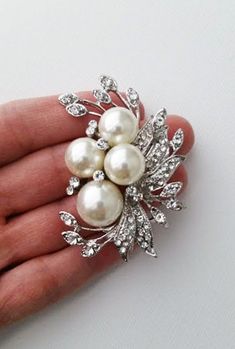 A pearl brooch is a decorative piece that accents and forms the shape of a neckline. A Pearl brooch is also known as a corsage pin. This brooch is a perfect accessory for the fall season. It features a large pearl and leaves with a rhinestones accent. It's the ideal way to add elegance and style to your everyday wear. ⭐   6 cm x 5m that is about 2.4" x 2" ⭐   Lead, cadmium, and nickel free ⭐   Pearl sizes are 14mm and 10mm ⭐   Pearl color is a soft ivory ⭐   Seriously unique for more brooches & pins https://www.etsy.com/shop/okqSupply?ref=seller-platform-mcnav§ion_id=27262035 Bridal Rhinestone Headpiece, Brooch Bouquet Diy, Brooch Wedding, Brooch Corsage, Bridal Brooch Bouquet, Rhinestone Headpiece, Wedding Brooch Bouquets, Corsage Pins, Bridal Accessories Jewelry