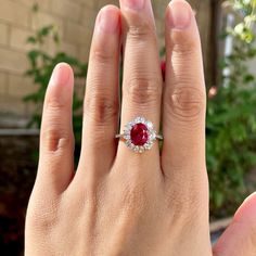 a woman's hand with a ring on it that has a red stone in the middle