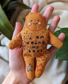 a hand holding a small orange stuffed animal with stars on it's body and eyes