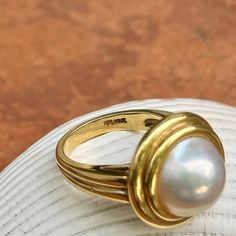 New, but old pieces, never worn, recently acquired from a premiere jeweler located in Minneapolis, MN for many years- a rare opportunity. 18KT yellow gold genuine, double bezel, round, mabe pearl ring Size 6.50 Sizable by us for a fee or your local jeweler Weight: 12.2 grams Band width: 3mm in back 11.50~12mm round mabe pearl Stamped 18k Luxury Pearl Ring With Bezel Setting, Timeless Gold Dome Ring With Cabochon, Mabe Pearl Rings, Classic Cabochon Pearl Ring For Formal Occasions, Luxury Yellow Gold Pearl Ring With Cabochon, Classic Formal Pearl Ring With Cabochon, Gold Oval Cabochon Pearl Ring, Anniversary Yellow Gold Pearl Ring With Cabochon, Oval Gold Pearl Ring With Cabochon