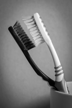 two toothbrushes sitting in a cup on a table