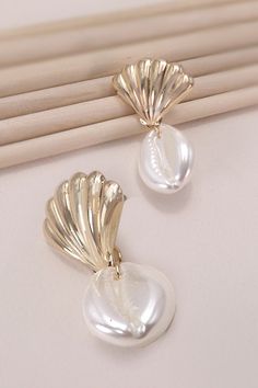 Crafted with care, these earrings feature delicate seashells and authentic puka shells dangling gracefully from each ear. Inspired by the serene allure of the ocean, they infuse your ensemble with a touch of seaside elegance. Perfect for adding a hint of beachy flair to any outfit, whether you're vacationing by the shore or simply longing for coastal vibes. Product Details:Width: 1"Length: 1.5"Earring back: PostMetal finish: gold, rhodium PlatedProduct: Lead & Nickel CompliantAnti-tarnish: Double E-coating Elegant Shell Dangle Earrings, Elegant Dangle Shell Earrings, Elegant Dangle Shell, Elegant Teardrop Jewelry For Beach, Elegant Teardrop Beach Jewelry, Elegant Shell Drop Earrings, Elegant Shell-shaped Earrings With Pearl Charm, Elegant Pearl White Shell For Beach, White Shell-shaped Pearl Earrings