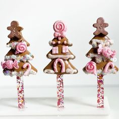 three gingerbread christmas trees with candy canes and candies in them on a white surface