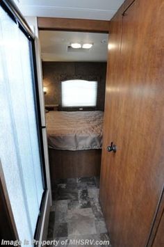 the inside of a travel trailer with a bed and closet doors open to reveal a bedroom