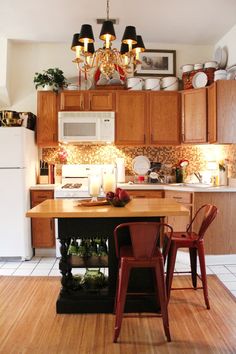 a kitchen with wooden cabinets and white appliances in the center is lit by candle lights