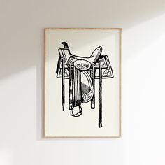 a black and white drawing of a horse saddle on a wooden frame hanging on the wall