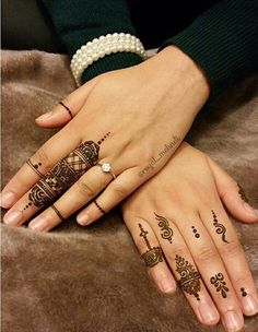 two hands with henna tattoos on them and one hand holding the other's finger