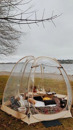 a tent set up in the grass near water