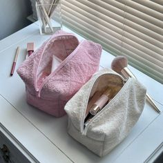 two makeup bags sitting on top of a white table