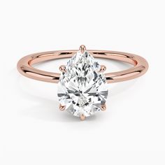 a rose gold engagement ring with an oval cut diamond in the center and shoulders, on a white background