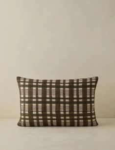 a black and white plaid pillow sitting on top of a table next to a wall