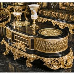 an ornately decorated coffee table sits in front of a black marble floor and gold accents