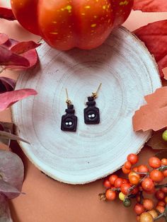 two black earrings sitting on top of a white plate next to berries and oranges